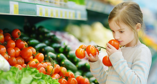Child with produce at grocery store